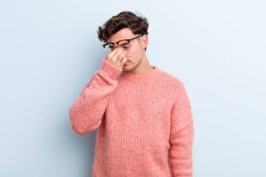 Genç yakışıklı, stresli, mutsuz ve hayal kırıklığına uğramış, alınlı ve şiddetli baş ağrısı çeken bir adam.