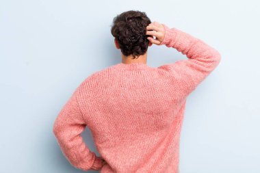 Genç yakışıklı bir adam bilgisiz ve kafası karışık hissediyor, bir çözüm düşünüyor, eli kalçasında, diğeri kafasında, dikiz aynasından.