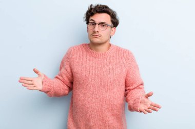 Genç yakışıklı adam şaşkın ve şaşkın hissediyor, doğru cevap veya karardan emin değil, bir seçim yapmaya çalışıyor.