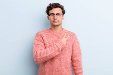 Genç yakışıklı adam kendini mutlu, pozitif ve başarılı hissediyor. Göğsünde el ile V şekli yapıyor. Zafer ya da huzur gösteriyor.