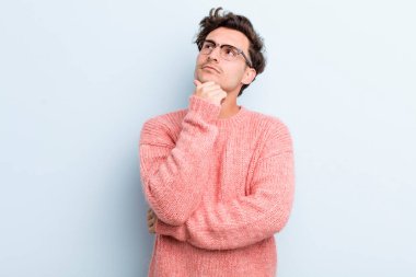 Genç yakışıklı adam düşünceli, meraklı ya da hayal kuruyor, hayal kuruyor ve mekanı kopyalamak için yukarı bakıyor.