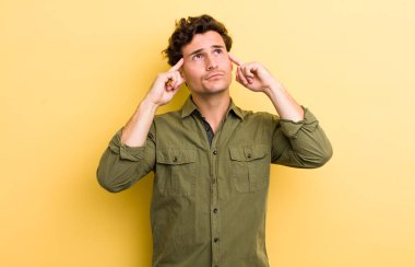 Genç ve yakışıklı bir adam kafası karışmış ya da şüphe içinde, bir fikre odaklanmış, çok düşünüyor, kenarda boşluğu kopyalamaya çalışıyor.