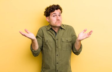 Genç yakışıklı adam şaşkın ve şaşkın, şüpheci, farklı seçenekleri tartıyor ya da komik bir ifadeyle seçiyor.