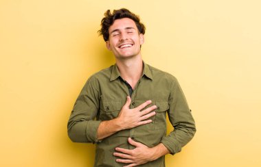 Genç yakışıklı adam komik bir şakaya yüksek sesle gülüyor, mutlu ve neşeli hissediyor, eğleniyor.