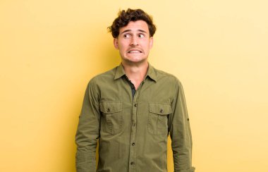 Genç, yakışıklı, endişeli, endişeli, korkmuş, panikleyen ve dişlerini sıkan bir adam.