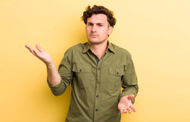 Şaşkın, şaşkın ve stresli görünen genç bir adam. Farklı seçenekler arasında merak ediyor. Belirsiz hissediyor.