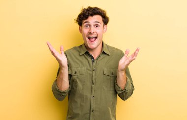 Genç yakışıklı adam mutlu, heyecanlı, şaşırmış ya da şok olmuş hissediyor, gülümsüyor ve hayrete düşüyor.