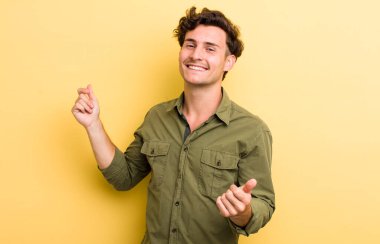 Genç yakışıklı adam gülümsüyor, kaygısız hissediyor, rahat ve mutlu, dans ediyor ve müzik dinliyor, bir partide eğleniyor.