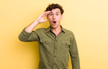 Genç yakışıklı adam mutlu, şaşkın ve şaşırmış görünüyor, gülümsüyor ve inanılmaz ve inanılmaz iyi haberleri fark ediyor.