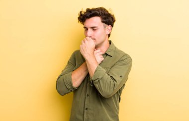 Gırtlağı ağrıyan, grip semptomları gösteren, ağzı kapalı öksüren genç yakışıklı bir adam.