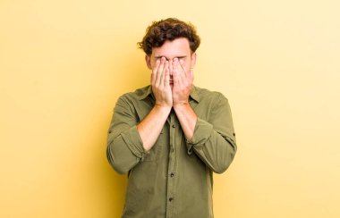 Genç yakışıklı adam üzgün, hayal kırıklığına uğramış, gergin ve depresif, iki eliyle yüzünü kaplayan, ağlayan