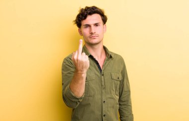 Genç, yakışıklı bir adam kızgın, sinirli, asi ve agresif orta parmağını sallayarak karşılık veriyor.