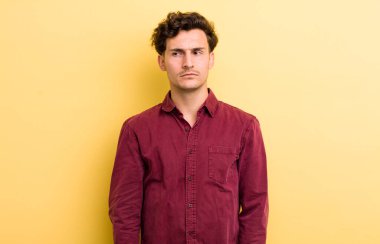 Genç, yakışıklı bir adam üzgün, üzgün ya da kızgın ve olumsuz bir tavırla, anlaşmazlık içinde somurtuyor.