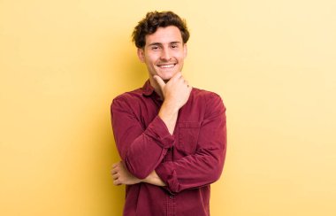 Genç yakışıklı adam gülümsüyor, hayattan zevk alıyor, mutlu, arkadaş canlısı, tatmin olmuş ve tasasız.