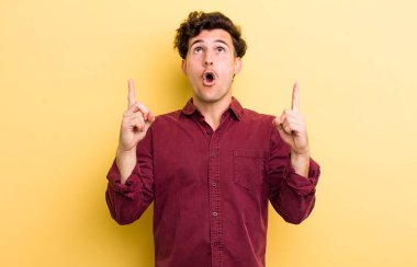 Genç yakışıklı adam şaşırmış, şaşırmış ve ağzı açık, iki eliyle uzayı göstererek