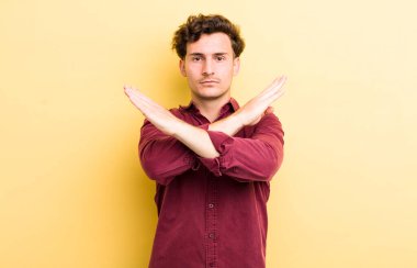 Genç ve yakışıklı adam senin tavırlarından rahatsız ve bıkkın görünüyor, yeter artık! Eller önde çapraz, durmanı söylüyor.