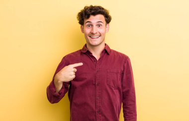 Genç yakışıklı adam mutlu, gururlu ve şaşırmış görünüyor, neşeli bir şekilde kendini gösteriyor, kendinden emin ve yüce hissediyor.