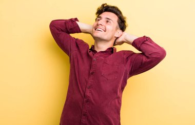 Genç yakışıklı adam gülümsüyor ve rahatlıyor, tatmin oluyor ve kaygısızca gülüyor.