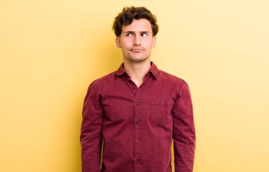 Genç ve yakışıklı adam kafası karışmış görünüyor, merak ediyor ya da bir sorunu çözmeye çalışıyor ya da düşünüyor.