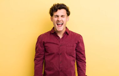 Genç yakışıklı adam agresif bir şekilde bağırıyor, çok kızgın, hayal kırıklığına uğramış, öfkeli ya da sinirli görünüyor, hayır