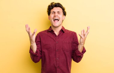 Genç yakışıklı adam öfkeyle bağırıyor, stresli hissediyor ve ellerini havaya kaldırıp neden ben diye bağırıyor.