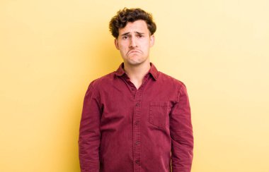 Genç yakışıklı adam üzgün ve mızmız, mutsuz bir bakışla, olumsuz ve hayal kırıklığına uğramış bir tavırla ağlıyor.