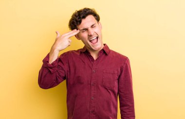 Genç yakışıklı adam mutsuz ve stresli görünüyor, intihar jesti silahla işaret ediyor, kafasını işaret ediyor.