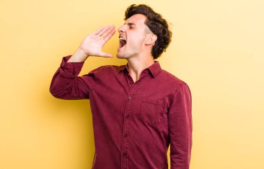 Genç yakışıklı adam öfkeyle bağırıyor kenardaki boşluğu kopyalasın diye, eli ağzının yanında.