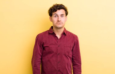 Aptal, çılgın, şaşkın bir ifadeyle genç yakışıklı adam, yanakları şişmiş, doldurulmuş, şişman ve yemekle dolu.