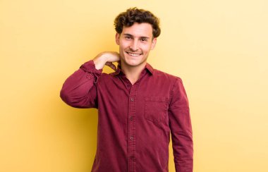 Genç ve yakışıklı bir adam neşeli ve kendinden emin bir şekilde gülüyor. Sıradan, mutlu, samimi bir gülümsemeyle.