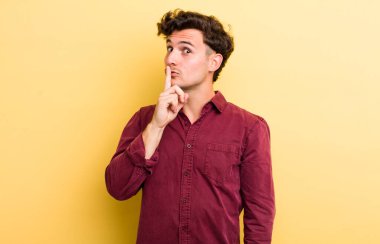 Genç yakışıklı adam sessizlik ve sessizlik istiyor, parmağıyla ağzının önünde işaret ediyor, 