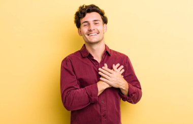 Genç yakışıklı adam romantik, mutlu ve aşık, neşeyle gülümsüyor ve kalbe yakın el ele tutuşuyor.