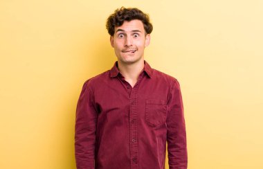 Şaşkın ve kafası karışmış genç bir adam gergin bir hareketle dudağını ısırıyor, sorunun cevabını bilmiyor.