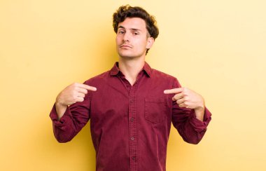 Genç yakışıklı adam gururlu, pozitif ve iki eliyle göğsünü gösteren