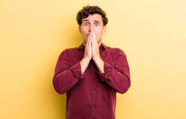 Genç yakışıklı adam endişeli, üzgün ve korkmuş, elleri ağızda, endişeli ve berbat görünüyor.