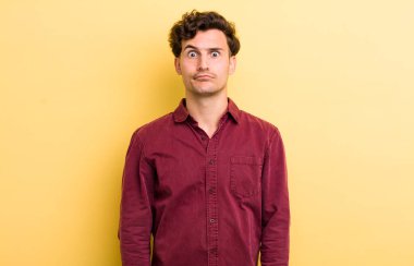 Genç ve yakışıklı adam şapşal ve komik görünüyor. Şaşı bakışlı, şakacı ve şakacı.