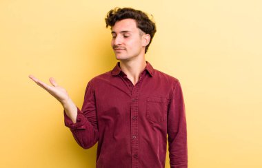 Genç yakışıklı adam kendini mutlu hissediyor ve gülümsüyor. Yanında duran bir nesneye ya da konsepte bakıyor.