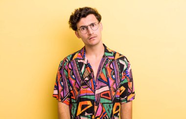 Genç yakışıklı adam şaşkın ve şaşkın hissediyor, aptal, afallamış bir ifadeyle beklenmedik bir şeye bakıyor.