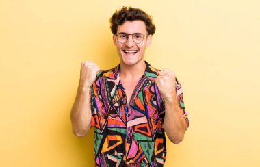 Genç yakışıklı adam zaferle bağırıyor, gülüyor, mutlu ve heyecanlı hissediyor başarıyı kutlarken.