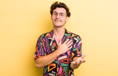 Genç yakışıklı adam mutlu ve aşık, bir eli kalbinin yanında, diğer eli önde uzanmış gülümsüyor.