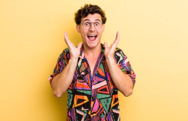 Genç ve yakışıklı bir adam beklenmedik bir sürpriz yüzünden şaşkın ve heyecanlı, güler yüzlü, şaşkın ve mutlu hissediyor.