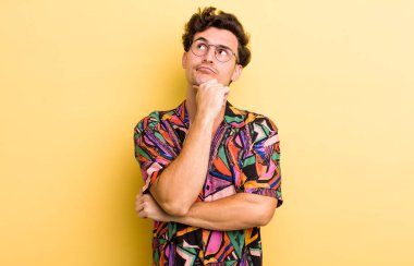 Genç yakışıklı adam düşünüyor, kuşkulu ve şaşkın hissediyor, farklı seçeneklerle, hangi kararı vereceğini merak ediyor.