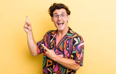 Genç, yakışıklı bir adam kendini neşeli ve şaşırmış hissediyor. Şok olmuş bir ifadeyle gülümsüyor ve bir tarafı işaret ediyor.