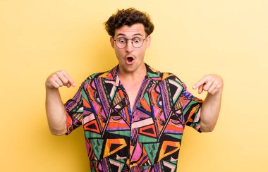 Genç yakışıklı adam şok olmuş, ağzı açık ve şaşkın, inançsızlık ve şaşkınlık içinde bakıyor ve onu işaret ediyor.