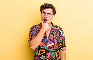 Ağzı ve gözleri açık, eli çenesinde genç ve yakışıklı bir adam. Hoş olmayan bir şok geçiriyor.