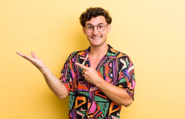 Genç yakışıklı adam neşeyle gülümsüyor ve bir objeyi göstererek veya reklamını yaparak avucundaki fotokopi alanını gösteriyor.