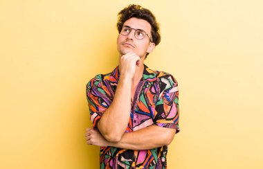 Genç yakışıklı adam düşünceli, meraklı ya da hayal kuruyor, hayal kuruyor ve mekanı kopyalamak için yukarı bakıyor.