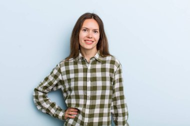 Genç ve güzel bir kadın mutlu bir şekilde gülümsüyor. Kendine güvenen, olumlu, gururlu ve arkadaş canlısı bir tavırla.