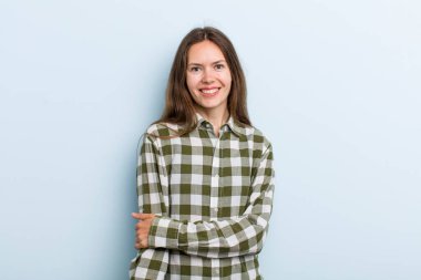 Genç ve güzel bir kadın utangaç ve neşeli bir şekilde gülüyor, arkadaş canlısı ve olumlu ama güvensiz bir tavırla.