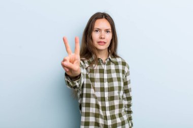 Genç ve güzel bir kadın gülümsüyor ve mutlu görünüyor, kaygısız ve pozitif, zafer ya da barışı simgeliyor.